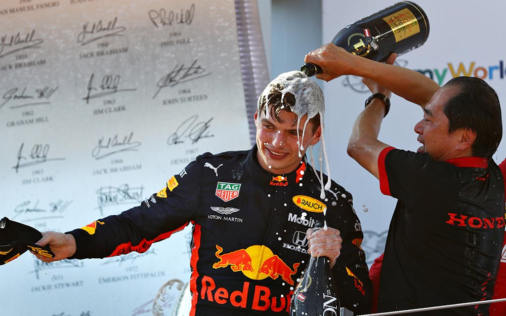 ホンダF1の現場統括責任者を務める田辺豊治テクニカル・ディレクターからシャンパンを浴びせられるレッドブルのマックス・フェルスタッペン、F1オーストリアGPの表彰台にて