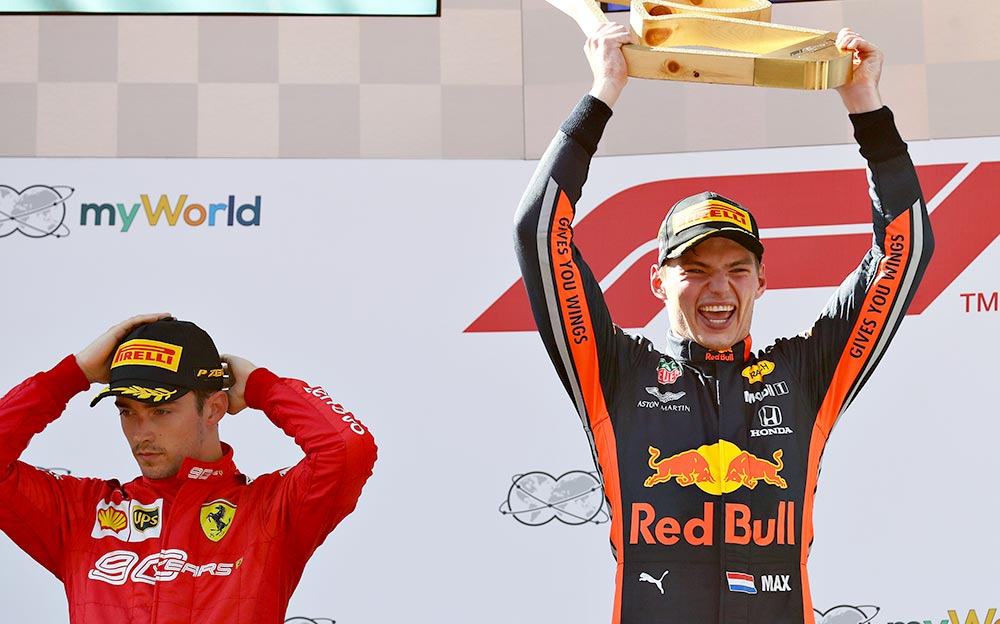 優勝トロフィーを手に満面の笑みを見せるレッドブル・ホンダのマックス・フェルスタッペンと、不機嫌な表情のフェラーリのシャルル・ルクレール、F1オーストリアGP決勝ポディウムセレモニーにて