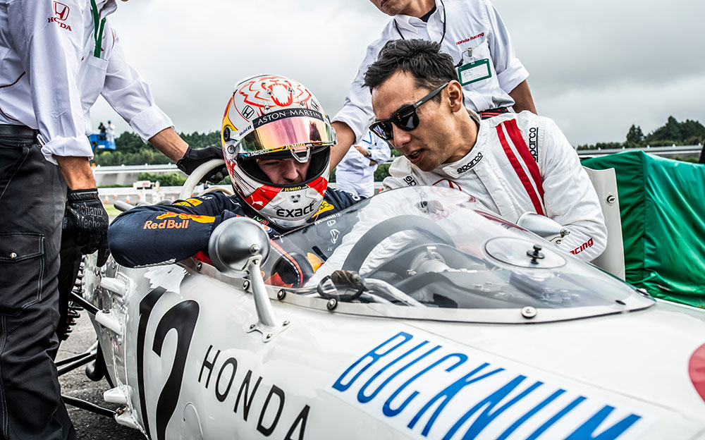 ホンダF1初のグランプリ優勝マシン「RA272」に乗り込むマックス・フェルスタッペンに指導する佐藤琢磨