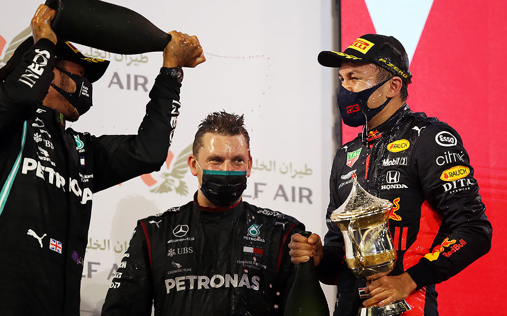 メルセデスAMGのルイス・ハミルトンからシャンパンの祝福を受けるレッドブル・ホンダのアレックス・アルボン、2020年F1バーレーンGP表彰台にて