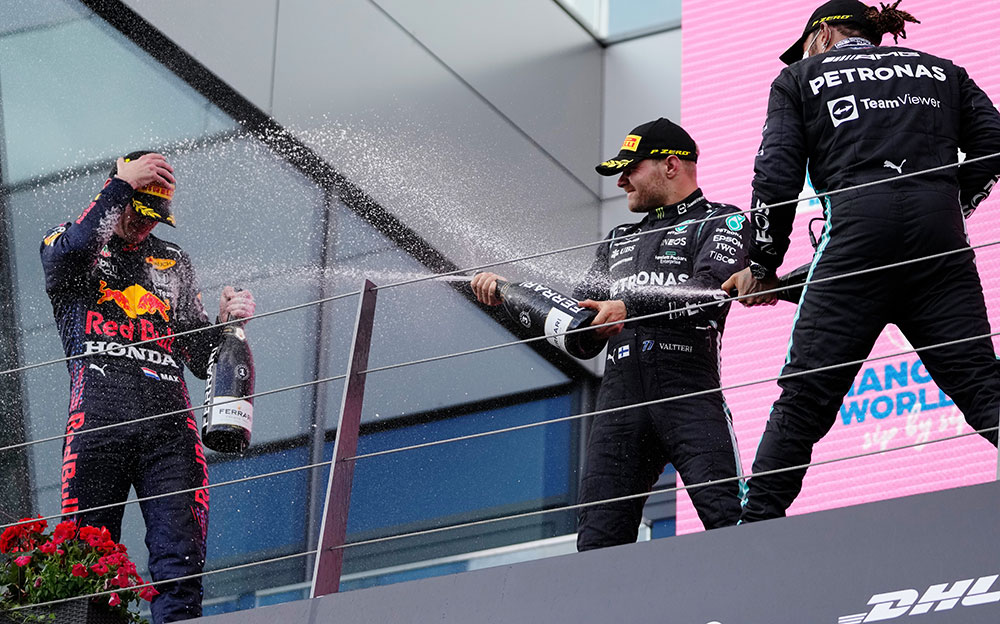 レッドブル・ホンダのマックス・フェルスタッペンにシャンパンを浴びせるメルセデスのルイス・ハミルトンとバルテリ・ボッタス、2021年6月27日F1シュタイアーマルクGPにて