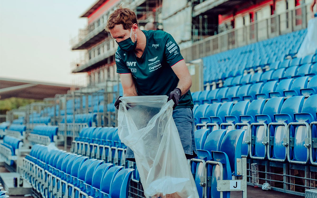 観客が去った後のシルバーストン・サーキットでゴミ拾いをするアストンマーチンのセバスチャン・ベッテル、2021年7月19日F1イギリスGPにて