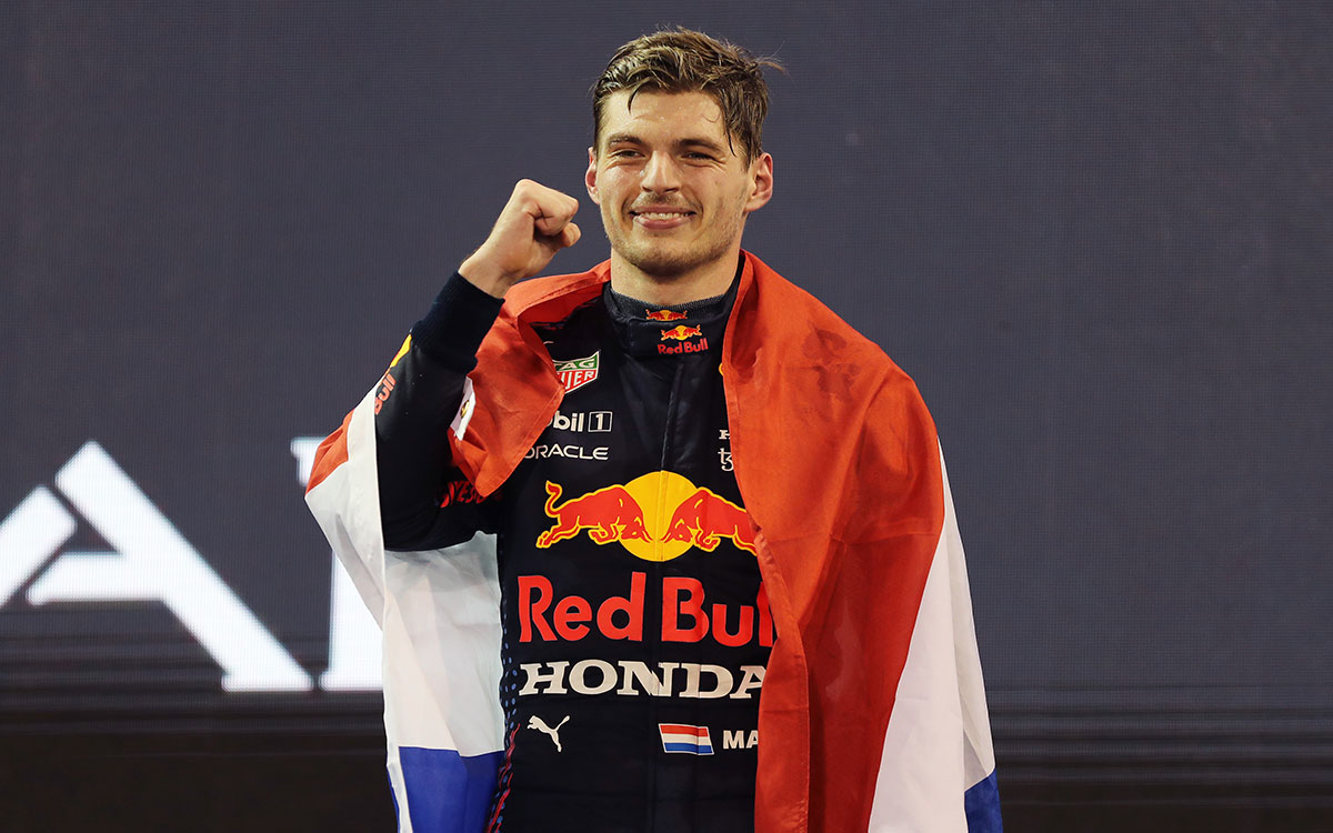 表彰台の上でオランダ国旗をまといガッツポーズを取るレッドブル・ホンダのマックス・フェルスタッペン、2021年12月12日F1アブダビGP決勝レースにて