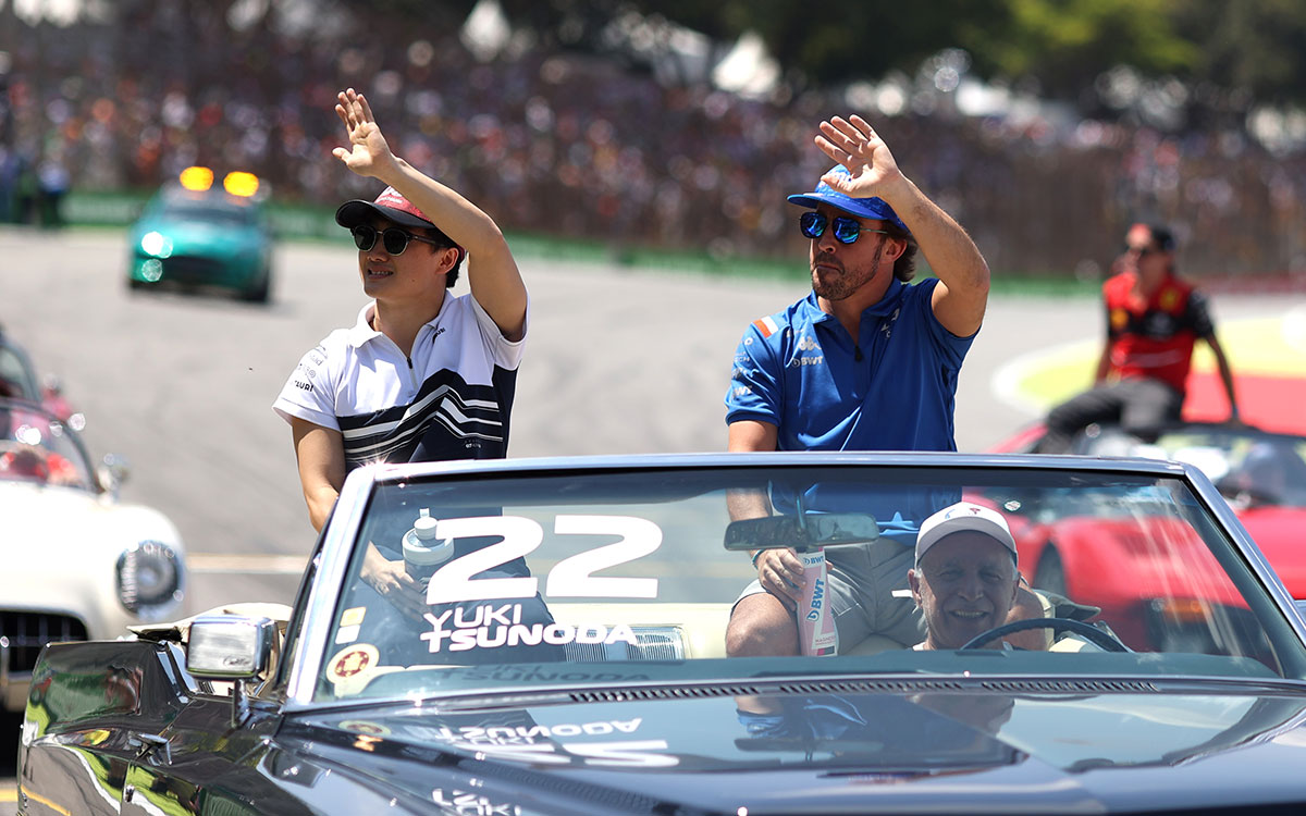 角田裕毅（アルファタウリ）が乗るクルマに同乗して観客に手を振るフェルナンド・アロンソ（アルピーヌ）、2022年11月12日F1サンパウロGPのドライバーズパレードにて