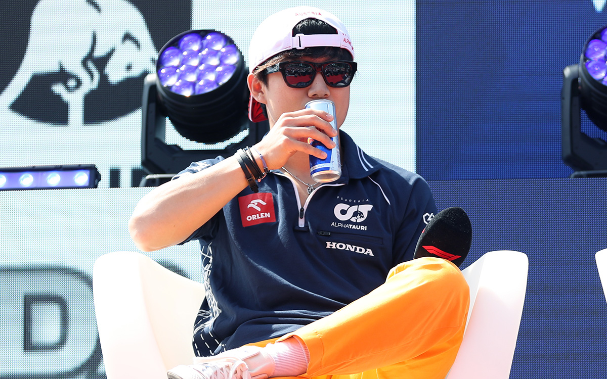 足を組み飲料を口にする角田裕毅（アルファタウリ）、2023年6月30日、F1オーストリアGP開幕前日のレッドブル・リンクで行われたファンステージにて