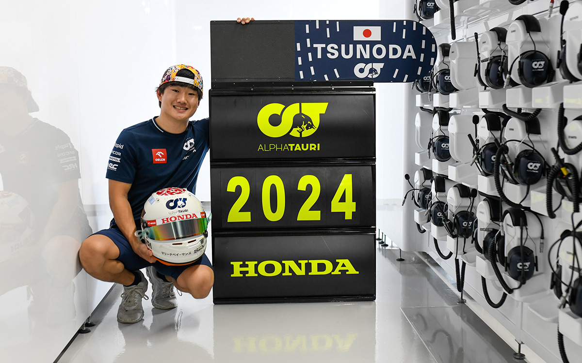 鈴鹿サーキットのパドックでスクーデリア・アルファタウリとの2024年契約延長を記念するピットボードの脇でポーズを採る角田裕毅、2023年9月23日F1日本GP