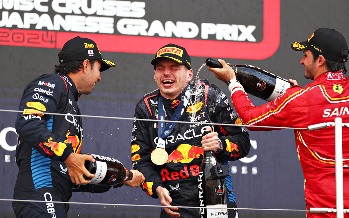 表彰台の上でレースウィナーのマックス・フェルスタッペン（レッドブル）にシャンパンをかける僚友で2位のセルジオ・ペレスと3位のカルロス・サインツ（フェラーリ）、2024年4月7日(日) F1日本GP（鈴鹿サーキット）