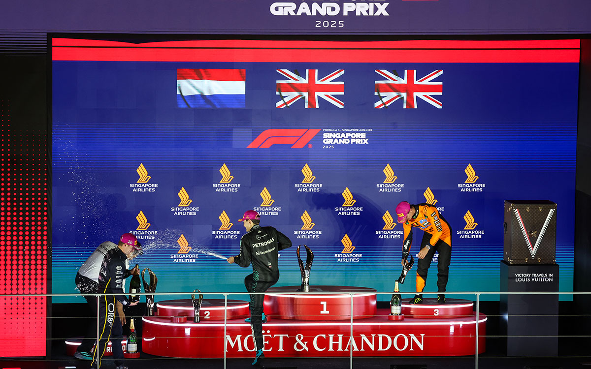 表彰台でシャンパンシャワーを楽しむ優勝者ジョージ・ラッセル(メルセデス)、2位マックス・フェルスタッペン(レッドブル)、3位ランド・ノリス(マクラーレン)、ペトロナスCEOのテンコ・ムハンマド・タウフィク、2025年10月5日(日) F1シンガポールGP決勝(マリーナベイ市街地コース)