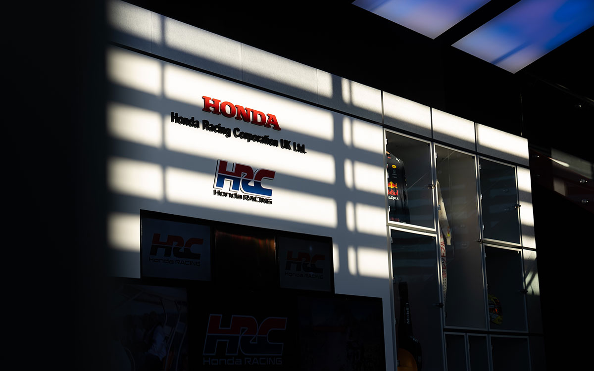 レーシングスーツが展示されたHRC UKの施設内壁面とロゴ看板