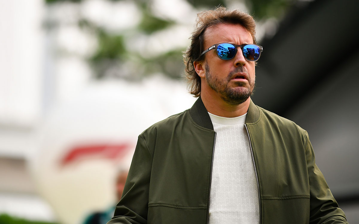 カーキ色のジャケットと青いミラーレンズのサングラスを着用してパドックを歩くフェルナンド・アロンソ(アストンマーティン・ホンダ)、2026年10月8日(木) F1シンガポールGPメディアデー(マリーナベイ市街地コース)