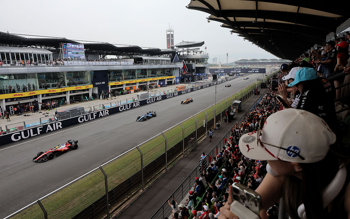 満員のグランドスタンド前のホームストレートを走行するF1マシンの一団、2026年10月4日(日) F1バーレーンGP決勝（セパン・インターナショナル・サーキット）