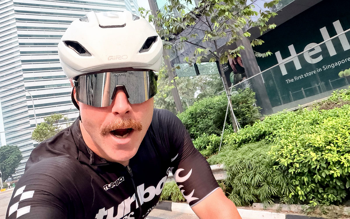 白いヘルメットとサングラスを着用し、シンガポール市街地を自転車で走りながら自撮りするバルテリ・ボッタス（キャデラック）、2026年10月7日(水) F1シンガポールGP開催地への約420kmの自転車移動を完走